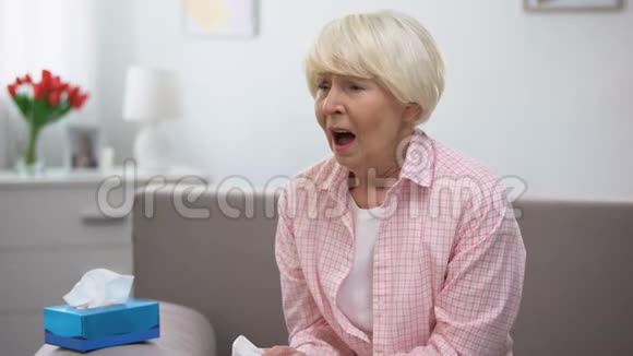 生病的老年妇女在家里打喷嚏感染流感病毒视频的预览图