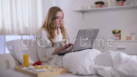漂亮的女孩在笔记本电脑上完成工作吃甜食糖做大脑视频的预览图