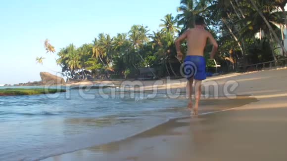 穿着蓝色短裤的男人在海浪中奔跑视频的预览图