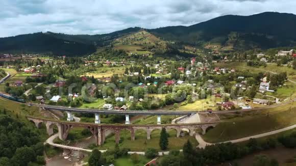 乘坐旧桥高架桥在山区和村庄之间的火车视频的预览图
