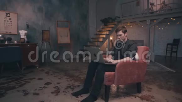 专业拍照视频拍摄特写库存录像年轻人坐在舒适的红色扶手椅上视频的预览图