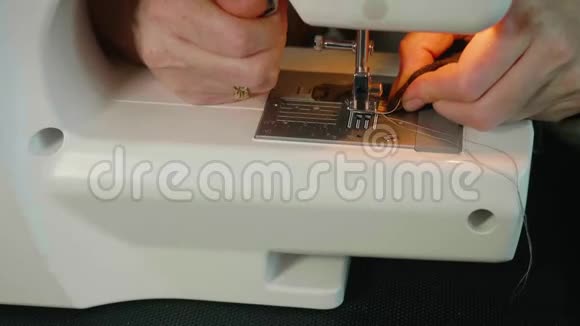 在电动缝纫机上合上女人的手缝制小灰色织物然后从出汗机上取出视频的预览图