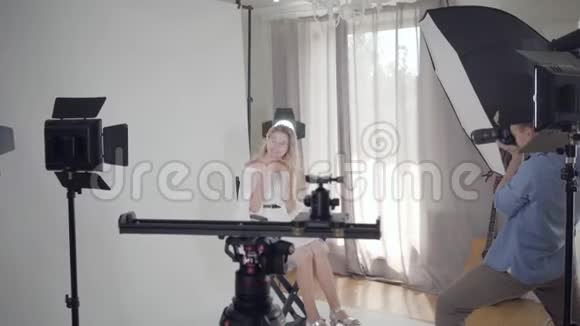 拍摄的后台著名男摄影师为坐在椅子上的迷人优雅女人拍照视频的预览图