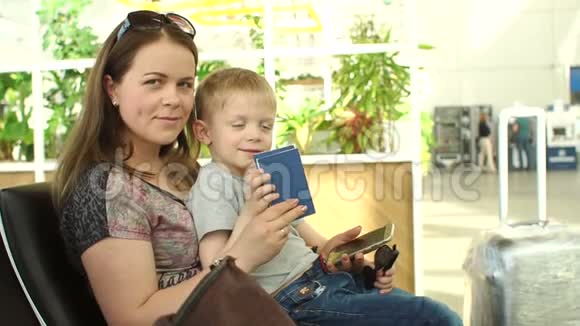 一位母亲带着孩子在机场候机室拿护照的画像视频的预览图