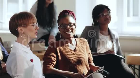 快乐年轻的多民族女性商业公司员工在现代办公会议上听研讨会大笑视频的预览图