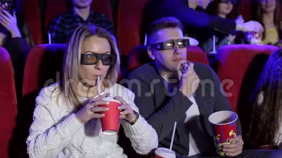 快乐的一对夫妻坐在电影院看3D电影吃爆米花微笑视频的预览图