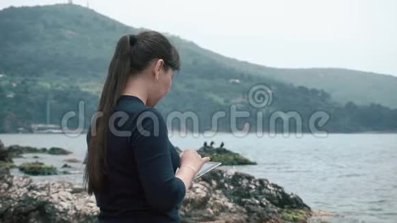 一个亚洲女孩欣赏美丽的风景手里拿着一个小玩意视频的预览图