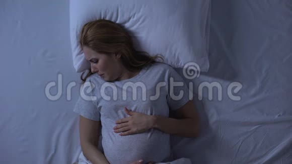 孤独期待的女人在床上哭泣抚摸着腹部绝望抑郁视频的预览图