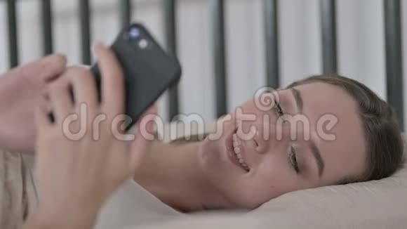 在床上使用模糊智能手机的年轻女子视频的预览图