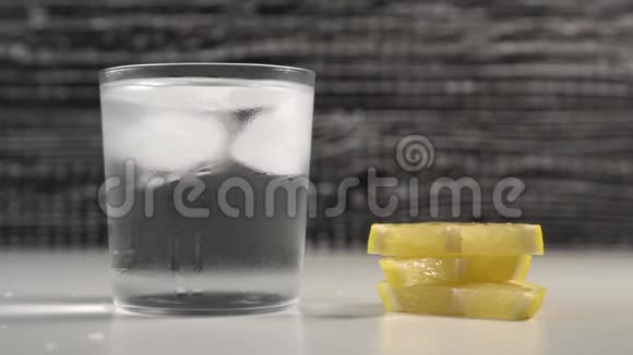 一管水和冰在一个蒸的玻璃上的黑白背景男人把柠檬片视频的预览图