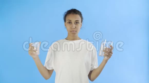 非洲裔美国女活动家蓝色背景的塑料杯和玻璃杯视频的预览图