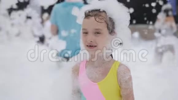 穿着泳衣的小女孩在白色泡沫中跳舞和跳跃视频的预览图
