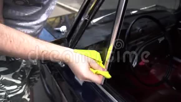 一名汽车服务工人用黄色抹布在一辆蓝色旧车上抛光铬零件视频的预览图