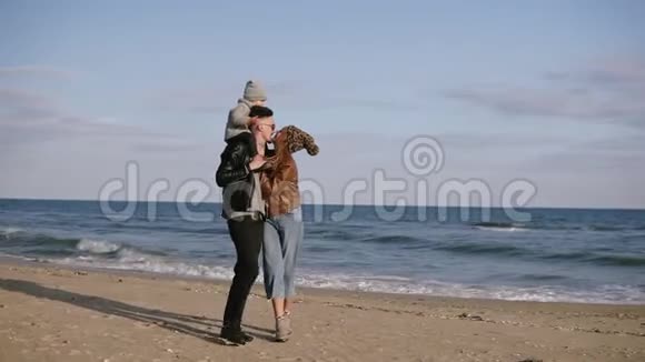 一个年轻的父亲把儿子扛在肩上一个年轻的家庭在海滨散步享受一个共同的周末A视频的预览图