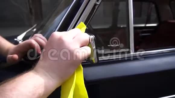 一名汽车服务工人用黄色抹布在一辆蓝色旧车上抛光铬零件视频的预览图