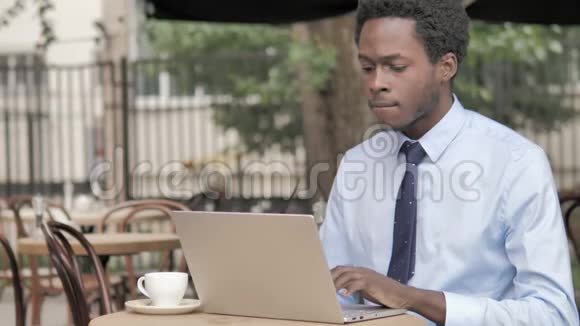 咳嗽的非洲商人在户外咖啡厅的笔记本电脑上工作视频的预览图