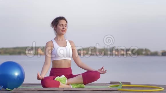 瑜伽疗法年轻美丽的瑜伽女性在莲花的位置冥想和享受精神平静的自然视频的预览图