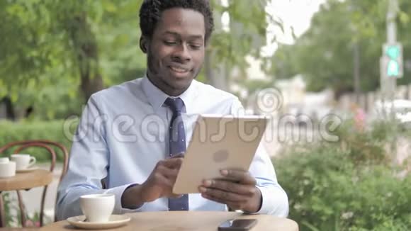 非洲商人在桌上在线视频聊天坐在户外咖啡厅视频的预览图