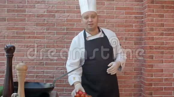 穿着白色制服的中年厨师站在办公桌旁手里拿着蔬菜和镜头说话准备视频的预览图