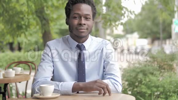 非洲商人竖起大拇指坐在户外咖啡厅视频的预览图