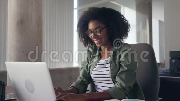 年轻女子坐在笔记本电脑前的办公桌前伸伸胳膊视频的预览图