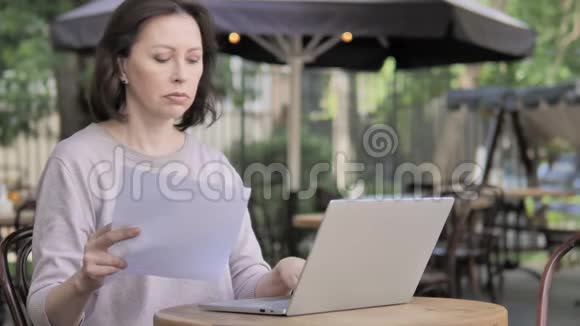 老年妇女在户外咖啡厅使用笔记本电脑的论文视频的预览图