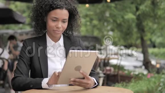非洲妇女在桌上在线视频聊天坐在户外咖啡厅视频的预览图