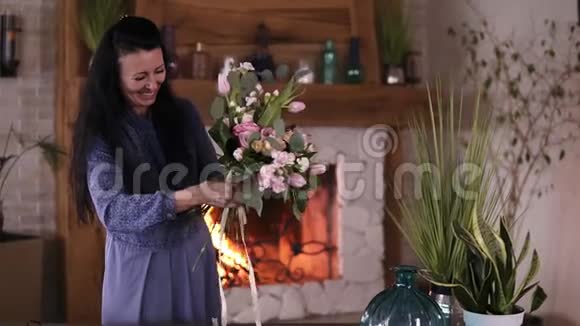 布鲁内特女士穿着蓝色连衣裙女花店轻轻地用丝带系上准备好的漂亮花束手工制作的花艺视频的预览图