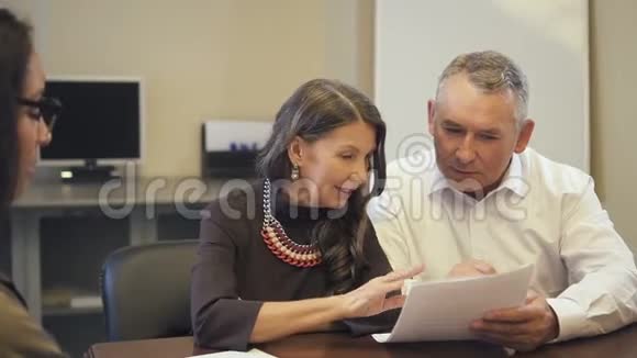 成熟夫妻在房地产中介机构阅读和讨论抵押合同视频的预览图