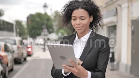非洲女商人在桌上的在线视频聊天站在户外的道路上视频的预览图