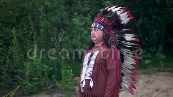 古老的美洲印第安人举起手来迎接站在森林的背景下视频的预览图