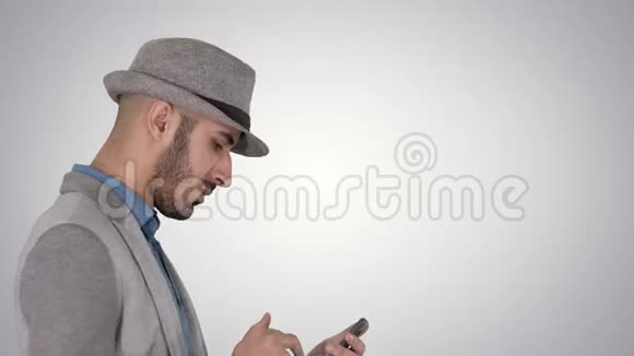 严肃的阿拉伯休闲男子使用智能手机而走在梯度背景视频的预览图