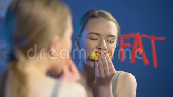 年轻女性咀嚼甜甜圈擦拭单词脂肪镜玻璃饮食紊乱健康视频的预览图