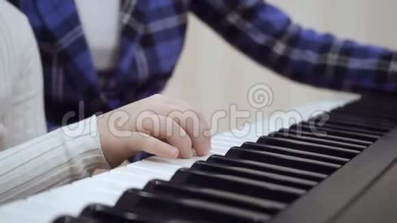 近距离观看儿童的手在钢琴上演奏视频的预览图