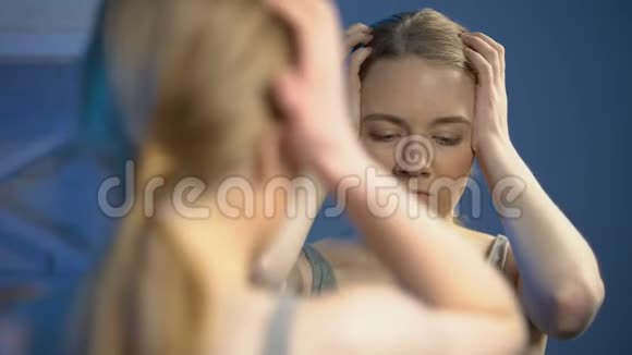 沮丧的女性悲伤地看着镜子不高兴的外表冷漠视频的预览图