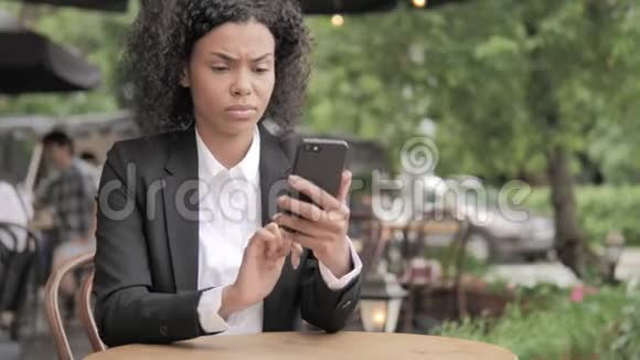 非洲妇女在智能手机上因失物招领坐在室外咖啡厅视频的预览图