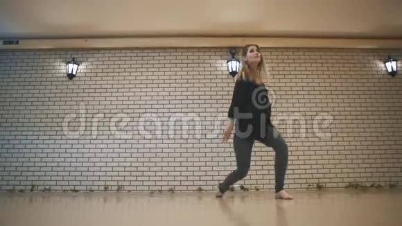 美丽的女孩穿着黑色的衣服在砖墙附近跳舞视频的预览图