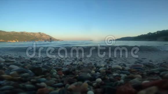 日落时Becici镇Budva附近的卵石和岩石海滩度假村海浪覆盖着摄像机它在水下视频的预览图