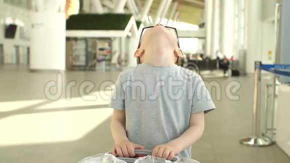 一个小男孩戴着太阳镜在国际机场大楼的肖像视频的预览图