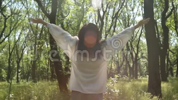 女人在阳光的森林里举手特写微笑轻松的女孩视频的预览图