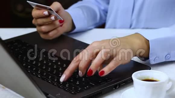女人在笔记本电脑上打信用卡数据关闭女性手持卡以便在电脑上进行在线支付视频的预览图