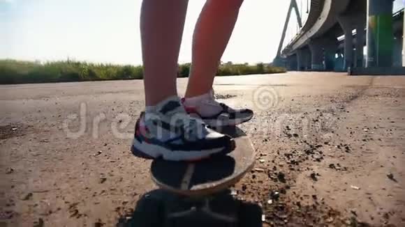 年轻女子穿着运动鞋骑着滑板在泥土上视频的预览图