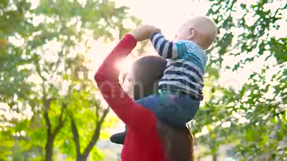 一位年轻的母亲和她的小儿子在夕阳的照耀下笑着旋转着玩耍着视频的预览图