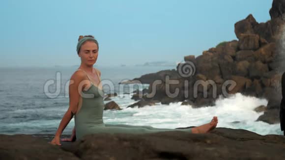 冷静的灰色女人坐在岩石海洋海岸慢动作视频的预览图