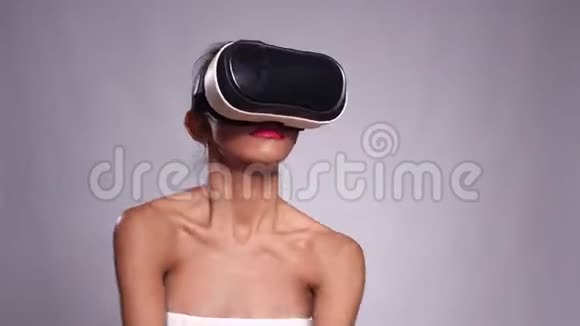 一个年轻漂亮的女孩戴着虚拟现实耳机或灰色墙壁上的3眼镜视频的预览图