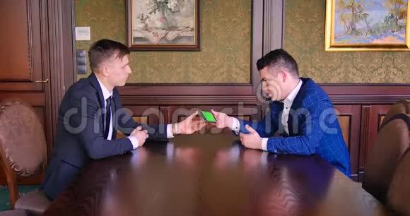 两个男商人同意并握手手机发色从手机上看创新视频的预览图