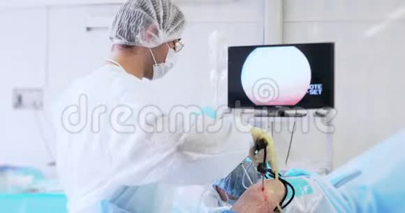 外科医生在使用外科腹腔镜器械进行手术时看监视器的背面视图医药视频的预览图