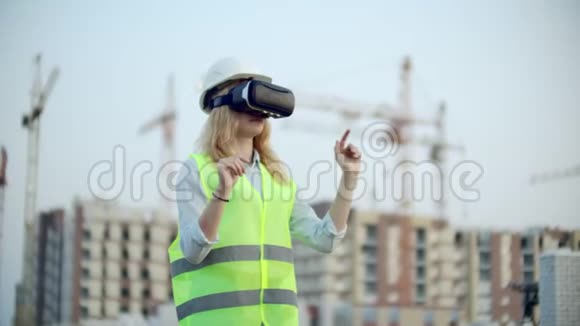 一位女性检查员用虚拟现实眼镜分析建设者工作的肖像一个戴着头盔的女人视频的预览图