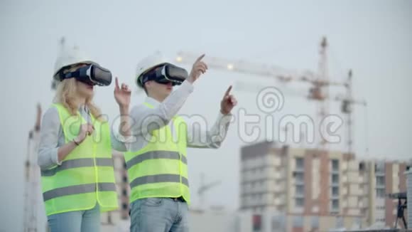 两个人一男一女戴着虚拟现实眼镜在建筑背景下使用起重机视频的预览图