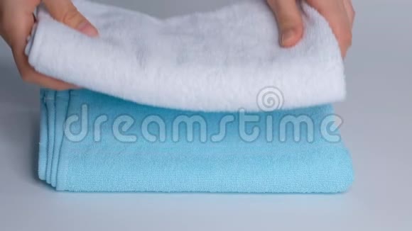 双手特写把一叠新的浴巾放在床单上客房服务员清洁酒店客房视频的预览图